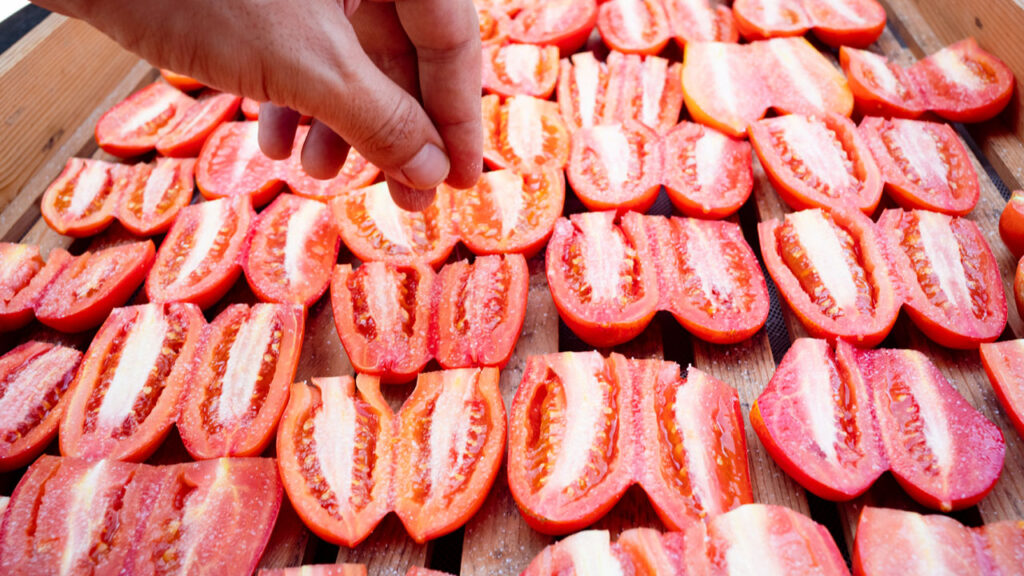 Hand putting salt on Tomatoes