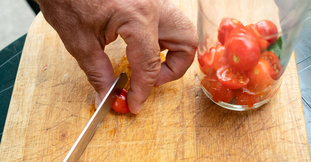 Hand cutting tomatoes in half